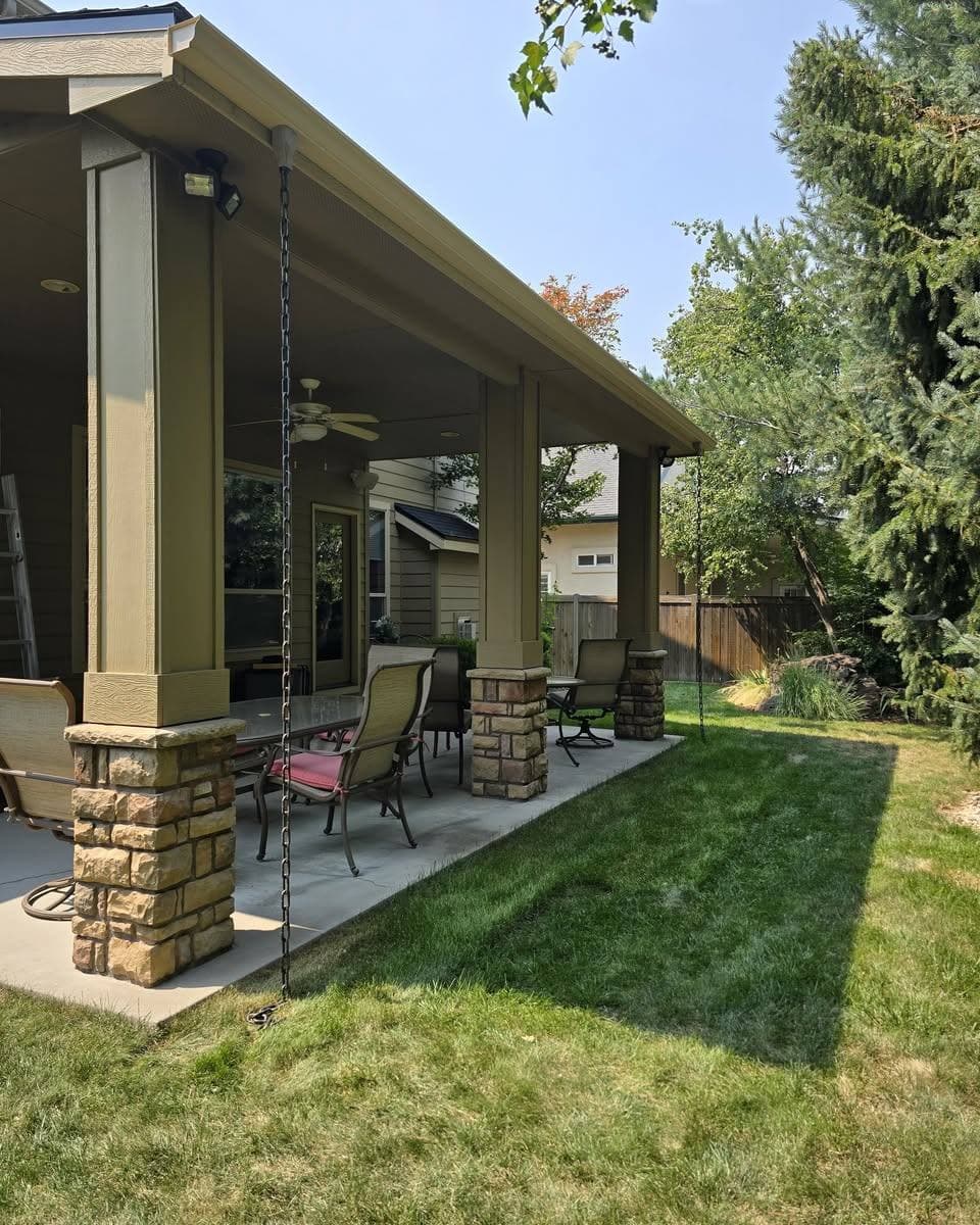 Rain chains carrying water down from a covered patio roof to ground anchors instead of a conventional downspout
